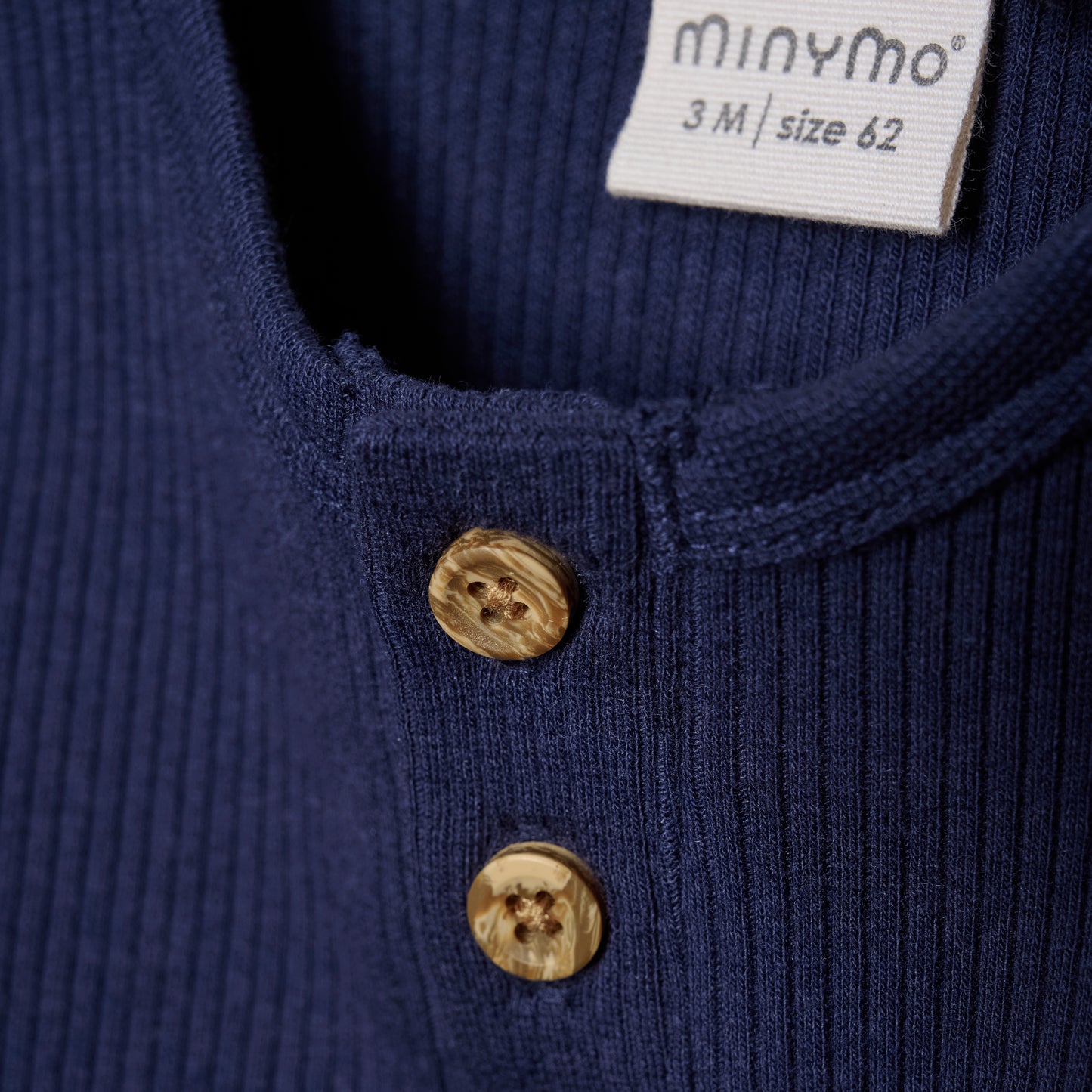 Der dunkelblaue Body von MINYMO besticht durch seine feinen Holzknöpfe und sorgt für stilvollen Komfort bei Ihrem Kind.