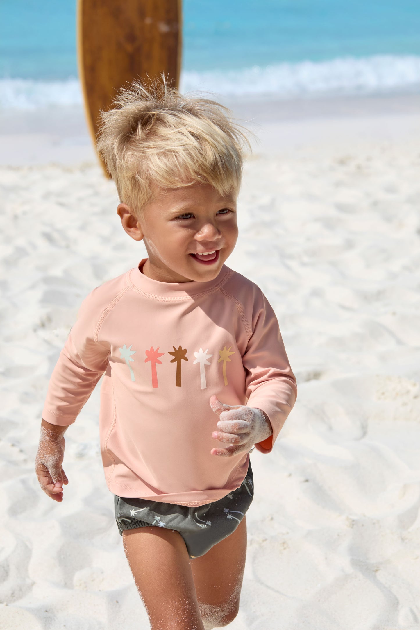Das rosa, langärmelige Kinder UV Shirt mit UV-Schutz 60 kommt mit einem Palmen Print und extra weichem Stoff. Das atmungsaktive und schnelltrocknende Material sorgt für eine angenehme Passform und Badespaß. Geeignet von 3 Monaten bis 3 Jahren.