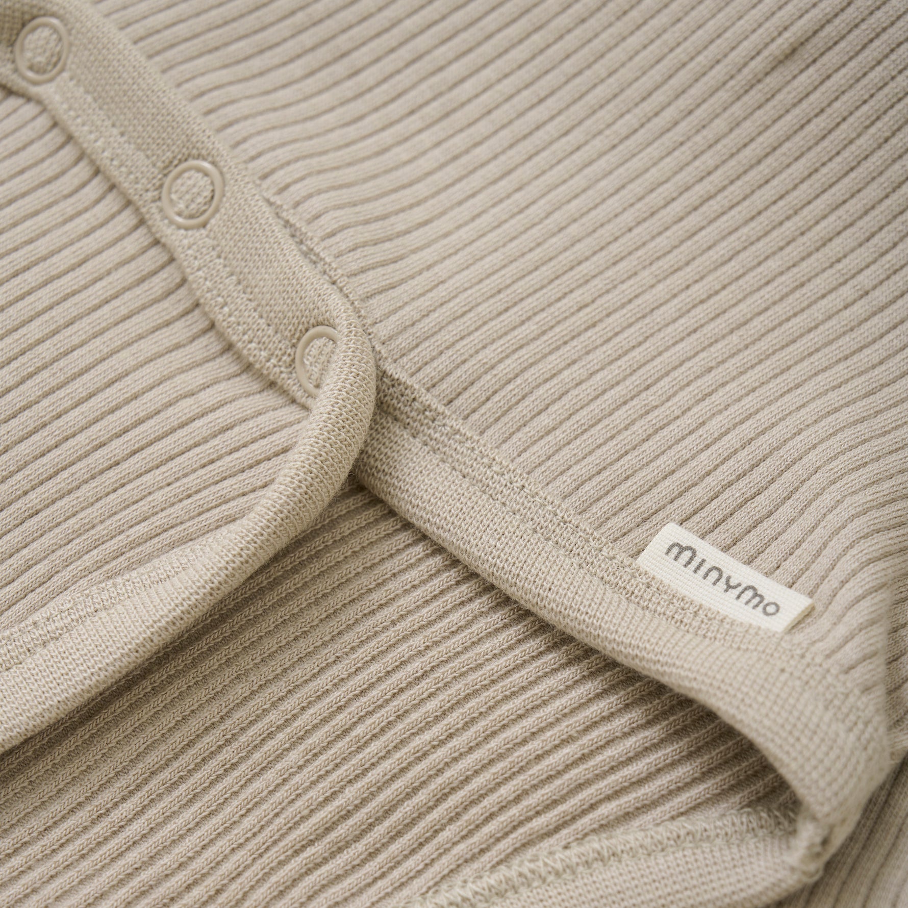 Der beige Body von MINYMO zeichnet sich durch seine feinen Holzknöpfe aus und überzeugt durch hochwertige Verarbeitung und angenehme Passform.