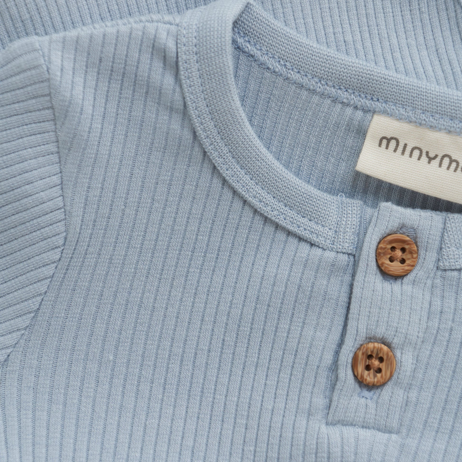 Dieser blaue Body von MINYMO ist mit zarten Holzknöpfen versehen und bietet eine angenehme Passform für Ihr Kind.