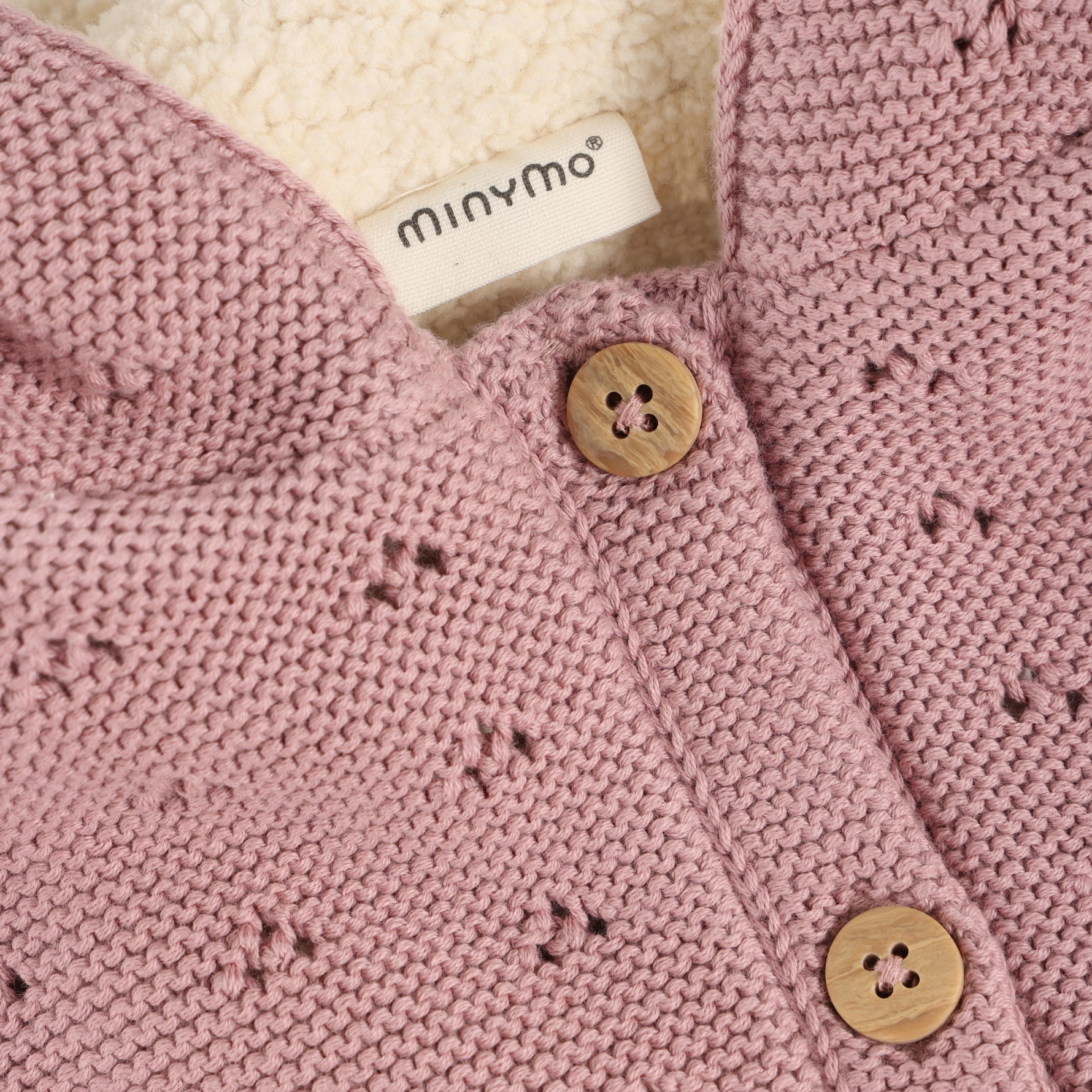 Die zart rosa Strickjacke von Minymo ist mit einem weichen Futter und einer Kapuze ausgestattet, die für zusätzlichen Schutz und Komfort sorgt. Dieses Design vereint funktionale Wärme mit einem ansprechenden Look, der sich ideal für die kühleren Tage eignet.&nbsp;