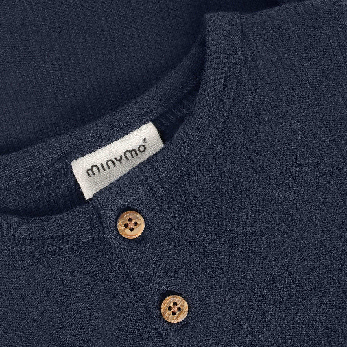 Ein eleganter langarm Rib Body in dunklem Blau von Minymo – perfekt für vielseitige Styling-Möglichkeiten. Die hochwertige Materialmischung aus Modal, Baumwolle und Elastane bietet optimalen Komfort und Bewegungsfreiheit für den Alltag.