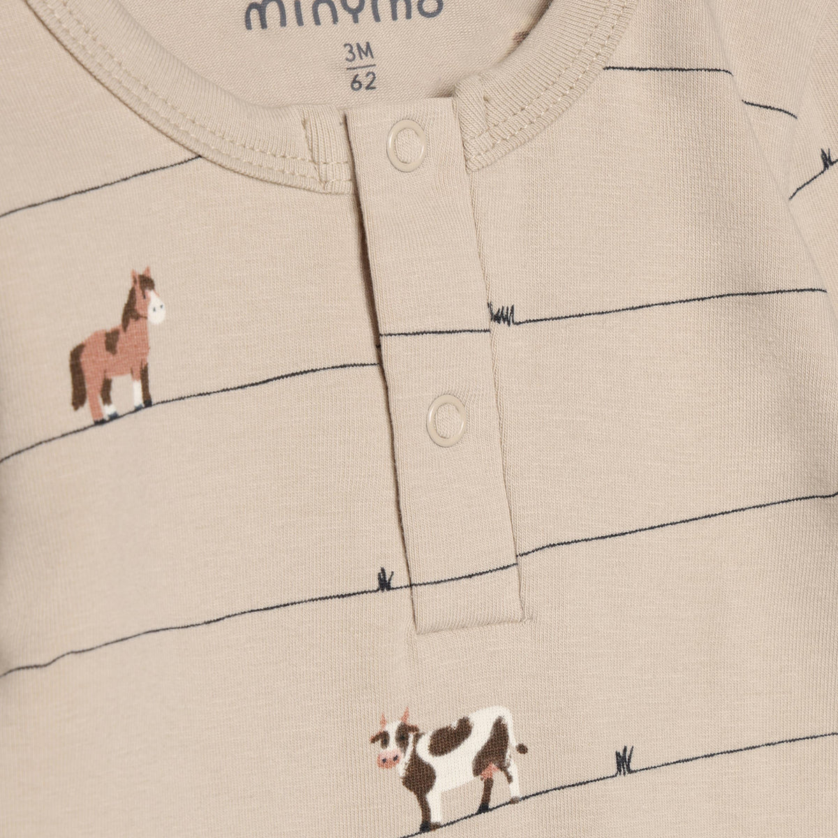 Langärmeliger Body aus der Minymo-Kollektion mit charmanten Farmtier-Motiven im All-Over-Print. Der Body besticht durch seine hochwertige Materialzusammensetzung aus 95% Baumwolle und 5% Elastane, die optimale Bewegungsfreiheit und Tragekomfort bietet. Perfekt für kleine Entdecker, die Stil und Funktionalität lieben.