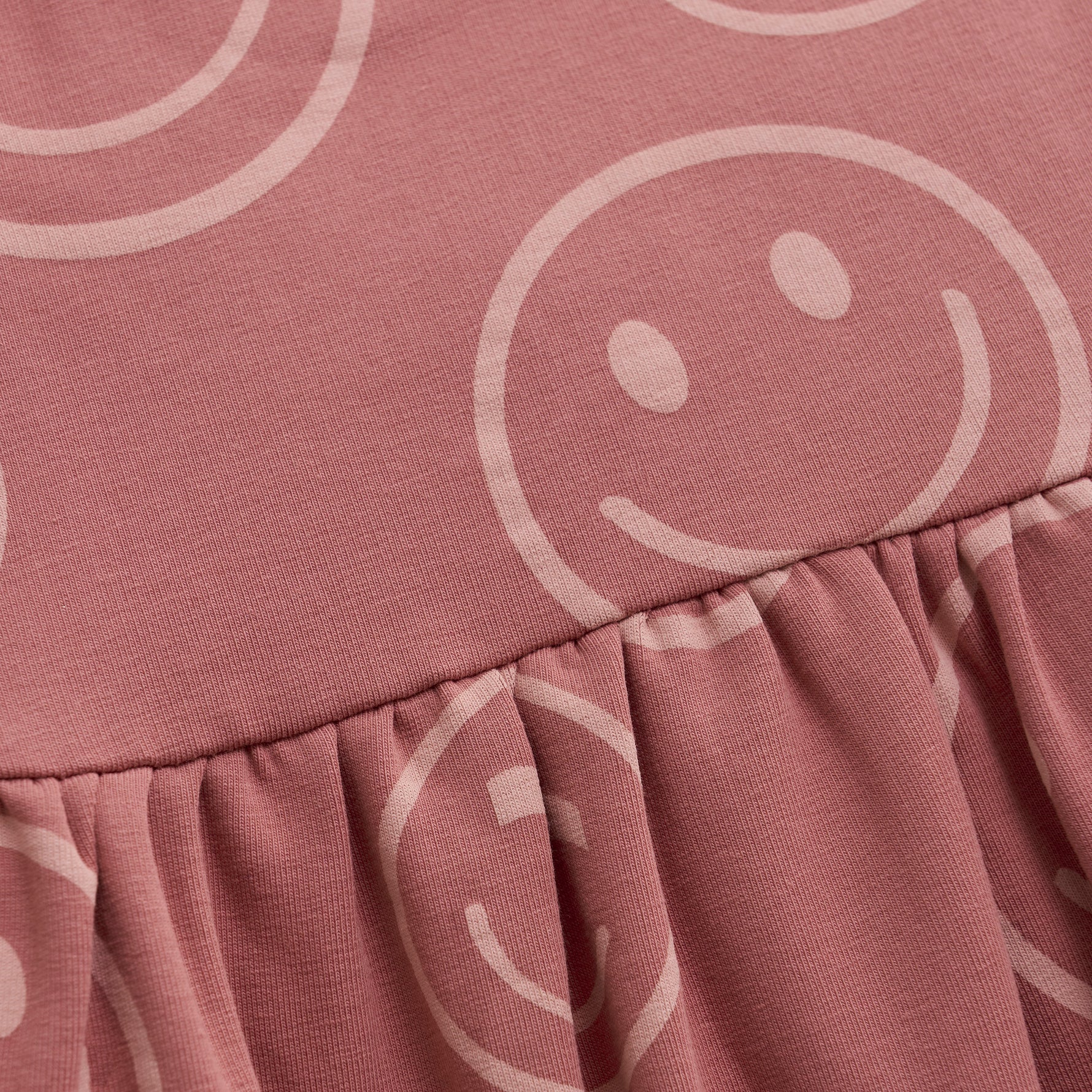 Dieses rosa Kleid von MINYMO ist mit einem fröhlichen Smiley-Motiv versehen und sorgt für gute Laune.