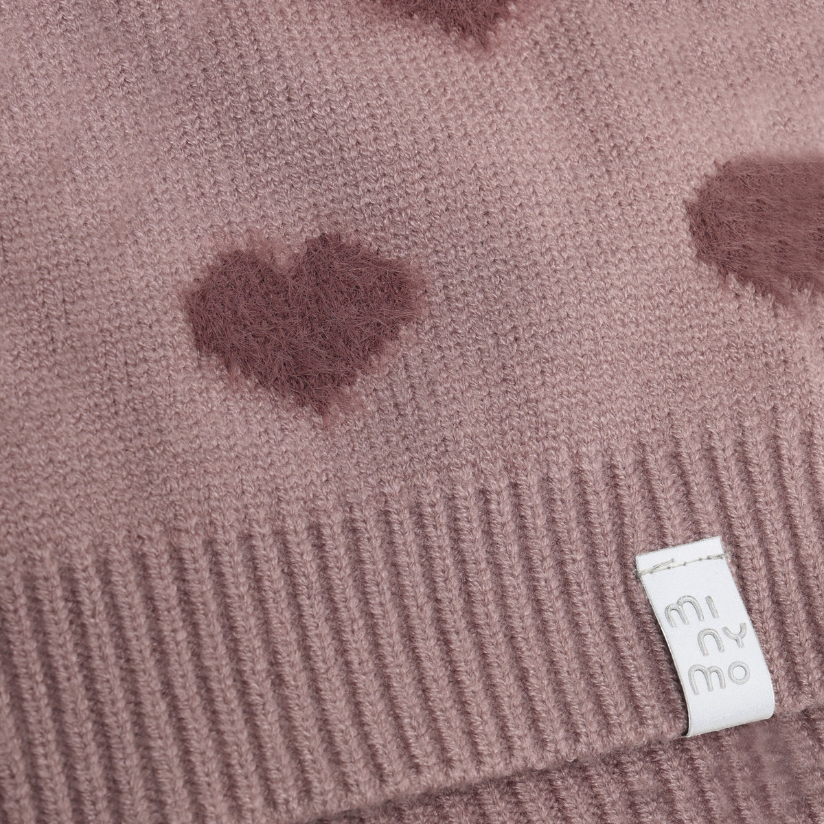 Weiche Teddy-Pile-Haube von Minymo in zartem Rosa mit niedlichem Herzmuster. Angenehm zu tragen und perfekt für kühle Tage. Aus hochwertiger Materialmischung: 52% Viscose, 28% Polyester und 20% Nylon für optimalen Komfort und Langlebigkeit.