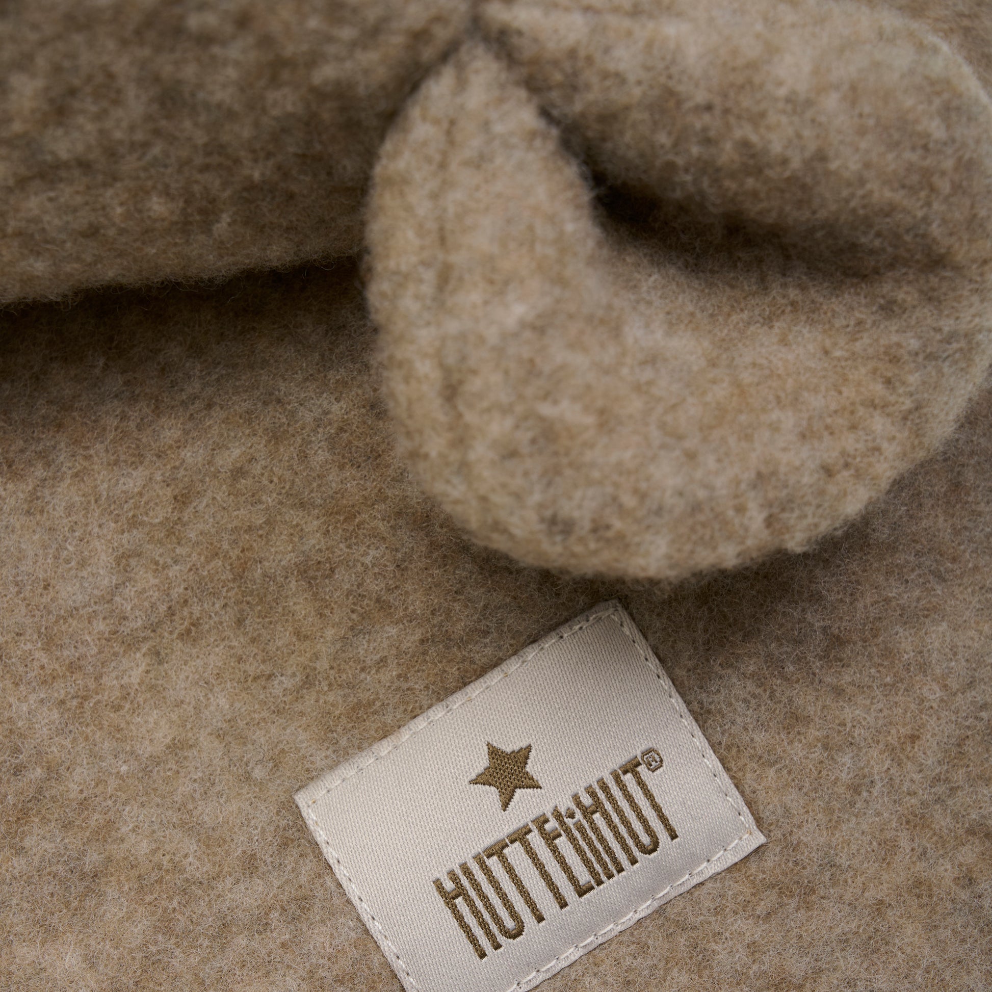 Diese beige Wollhaube mit Ohren von Huttelihut verbindet kuschelige Wärme mit verspieltem Design – perfekt, um stilvoll durch kalte Tage zu kommen.