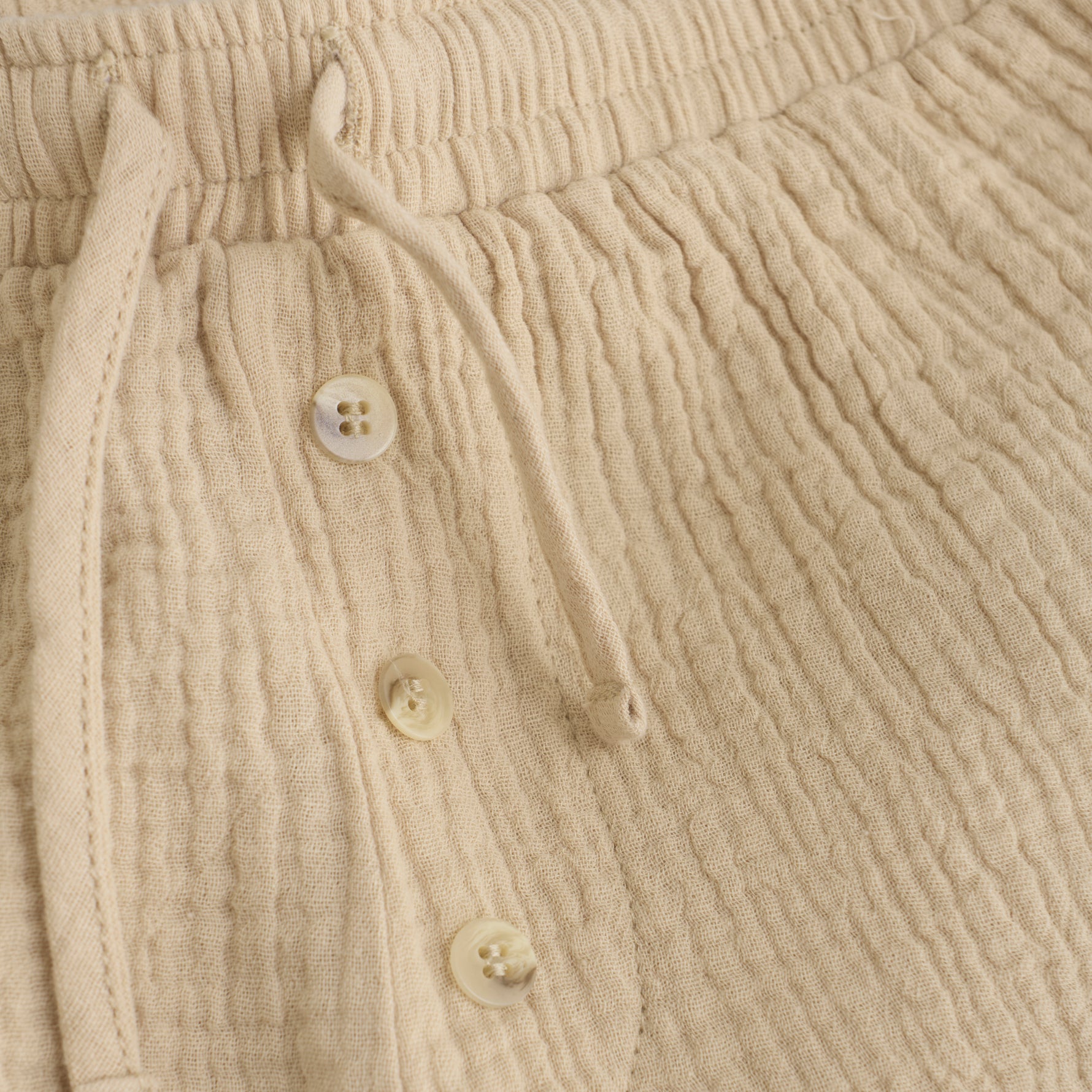 Diese kurze beige Musselin-Short bietet ein leichtes, atmungsaktives Tragegefühl – perfekt für warme Tage. Ihr weicher Stoff sorgt für angenehmen Komfort, während der lockere Schnitt Bewegungsfreiheit garantiert.&nbsp;