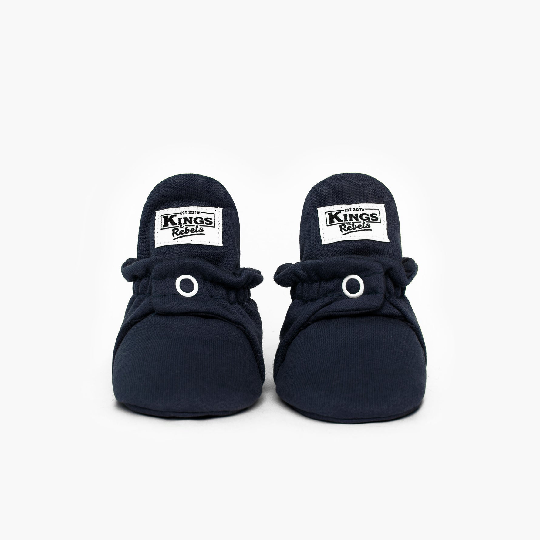 Die Kings &amp; Rebels Baby Booties wurden mit einem einfachen und praktischen Druckknopf- Verschluss entworfen, was das Anziehen von strampelnden Babys in wenigen Sekunden ermöglicht.

Der komplett um die Ferse verlaufende und über dem Knöchel sitzende, integrierte Gummizug verhindert auch bei sehr aktiven Babys das Herunterrutschen des Booties.

Alle Modelle der ´Cotton Classic´ und ´Cotton Gripper´ Linie sind aus haut- und umweltfreundlicher Baumwolle gefertigt, was für hohen Tragekomfort auch bei frühli