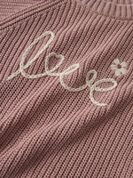 Das rosa Strickoberteil von Lil'Atelier besticht durch seinen liebevollen Love-Schriftzug und verleiht jedem Outfit eine charmante Note.