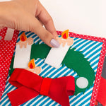 Das Mini Quiet Book Christmas von Jolly Designs begleitet Kinder ab 18 Monaten durch die Weihnachtszeit. Mit sechs interaktiven Seiten trainieren sie Feinmotorik und Kreativität – vom Schmücken des Tannenbaums bis zum Zählen der Adventskerzen. Aus OEKO-TEX® zertifizierten Materialien gefertigt, ist es sicher, robust und ideal für kleine Hände.
