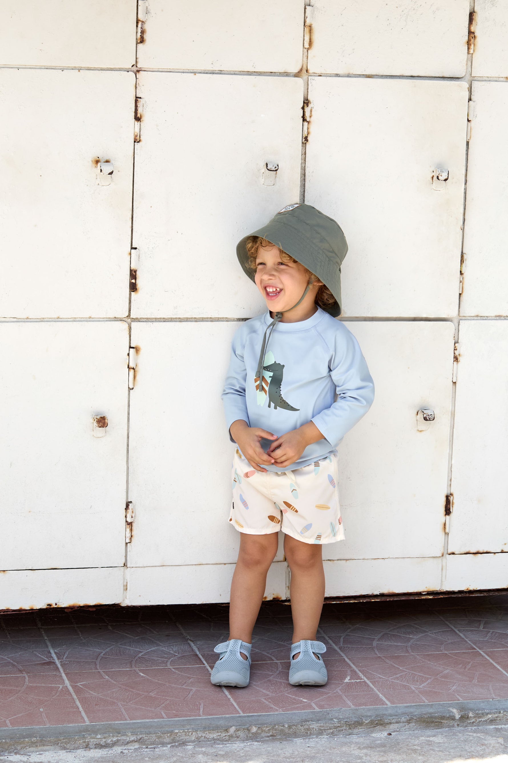 Das hellblaue, langärmelige Kinder UV Shirt mit UV-Schutz 60 kommt mit einem Crocodile Print und extra weichem Stoff. Das atmungsaktive und schnelltrocknende Material sorgt für eine angenehme Passform und Badespaß. Geeignet von 3 Monaten bis 3 Jahren.