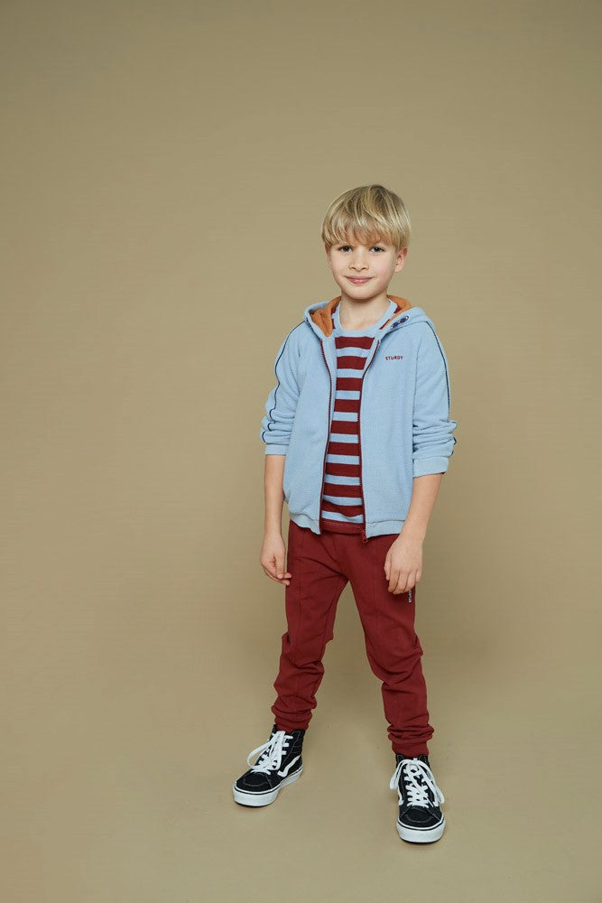 Dieses rot-blaue, gestreifte Langarmshirt aus der Waves and Whales Kollektion von Sturdy überzeugt mit seinem gerippten Material und einem dezenten Anker-Detail – perfekt für einen maritimen Look mit Stil.