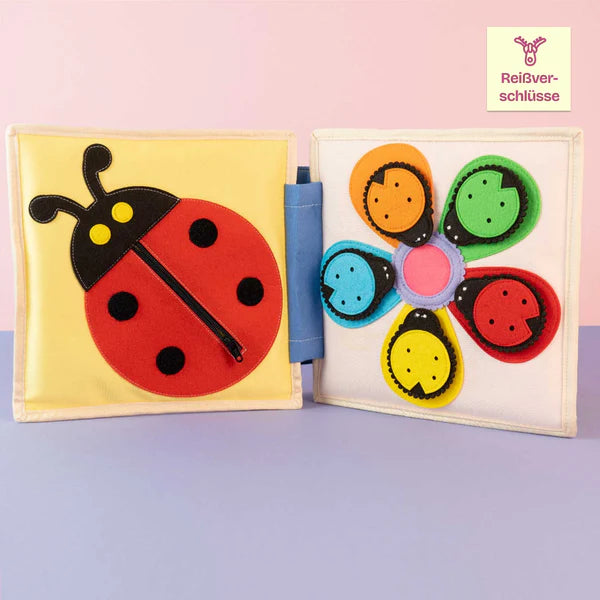 Das Quiet Book Pastell Junge Eule ist ein liebevoll handgefertigtes Stoffbuch, das Kinder ab 12 Monaten auf eine bunte Entdeckungsreise einlädt. Mit farbenfrohen Formen, einem Marienkäfer mit Reißverschluss, lustigen Fingerpuppen und einem Regenbogen zum Knöpfen verbindet dieses Buch motorische Übungen mit kreativem Spiel. Kinder lernen Farben und Formen kennen, trainieren Geduld und Geschicklichkeit und tauchen in kleine Geschichten ein, die mit den Figuren lebendig werden.