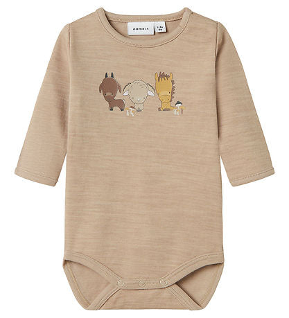 Hübscher Name It Body in meliertem Beige mit einem niedlichen Print verschiedener Tiere, darunter Pferde, Schafe und Ziegen.

Der Name It Body hat lange Ärmel und wird über der linken Schulter mit versteckten Druckknöpfe und mit regelmäßigen Druckknöpfe zwischen den Beinen geöffnet, was das An- und Ausziehen erleichtert.